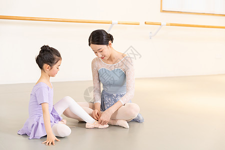 芭蕾舞老师帮助小女孩系鞋带图片