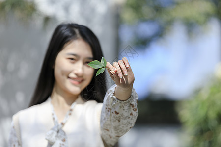 美女大学生拿叶子遮挡眼睛图片