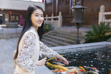 景区游客美女大学生逛寺庙喂食金鱼背景