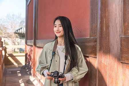 青春美女大学生背着相机旅行拍照背景图片