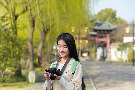 青春美女大学生背着相机旅行拍照图片