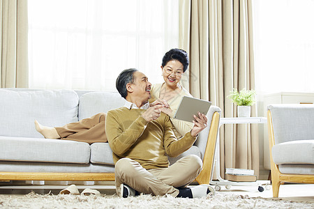 快乐的老年夫妇在客厅使用平板电脑图片