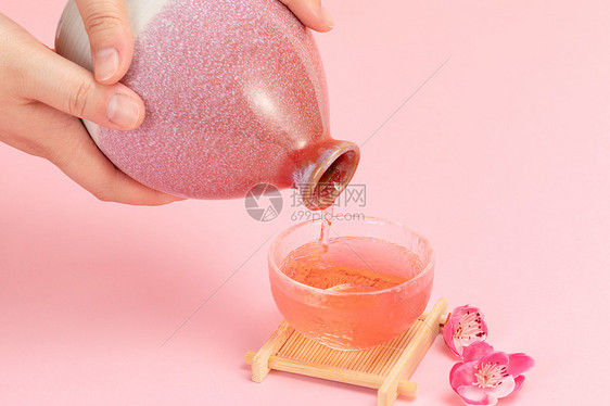 粉色背景桃花酒倒入酒杯图片