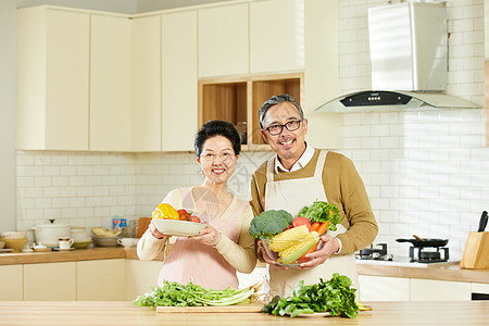 手捧菜厨房里中老年夫妇手捧新鲜蔬菜背景
