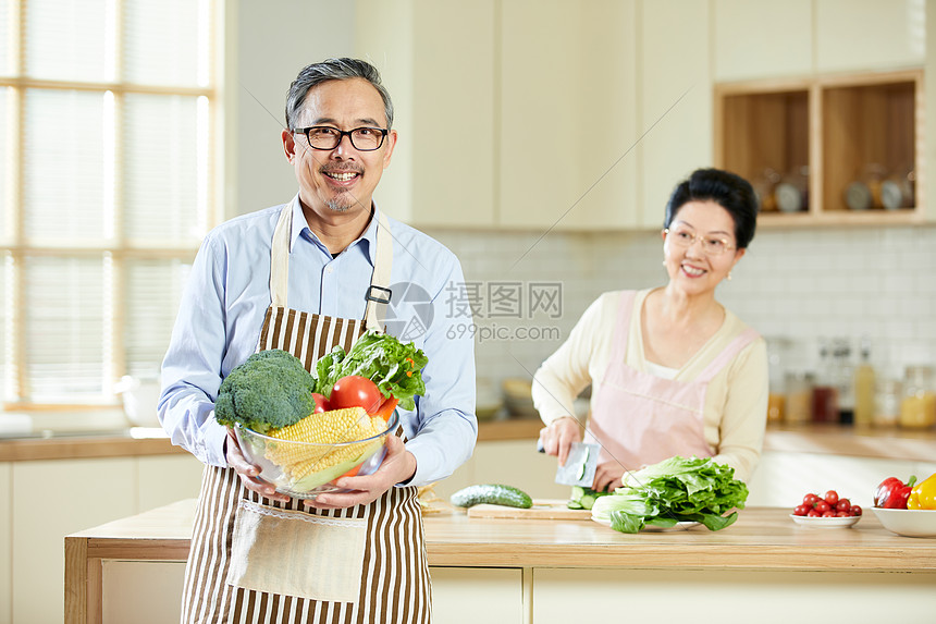 厨房里中老年男士手捧新鲜蔬菜图片