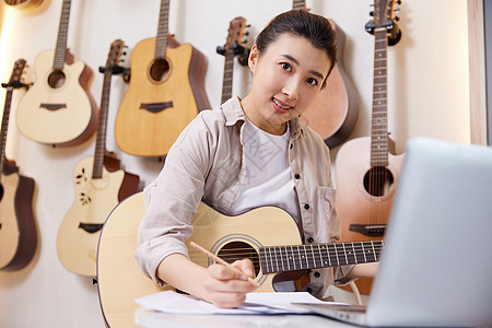 女性面对电脑学习吉他高清图片