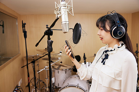 录音棚内拿着手机唱歌的女性图片素材