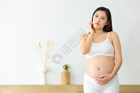 捧着肚子表情疑惑的孕妇图片