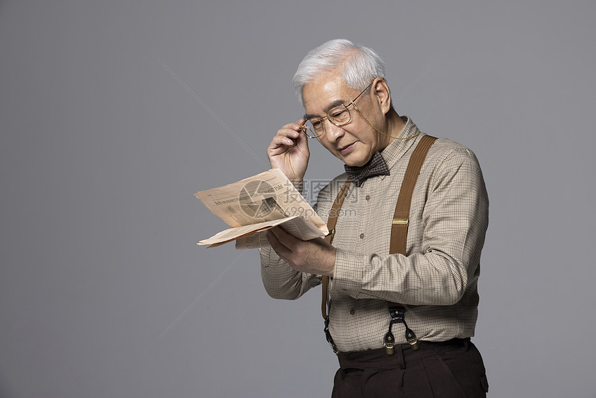戴眼镜看报纸的老年人
