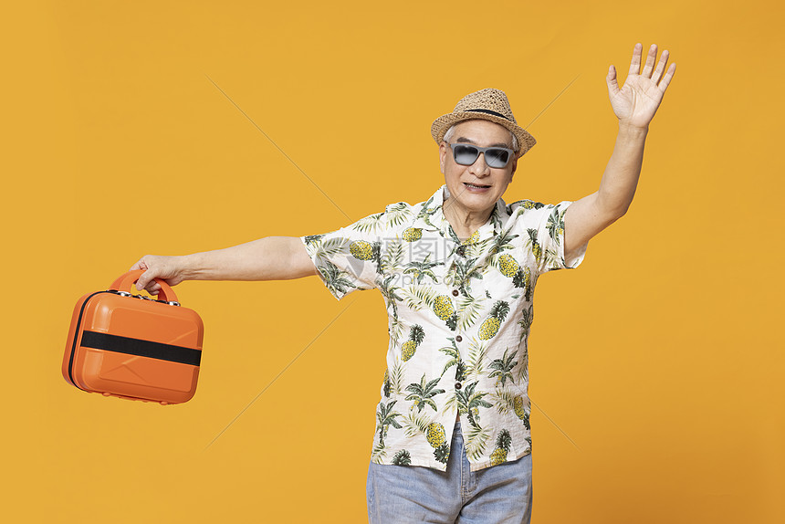 穿着短袖提着手提箱旅游的老人挥手