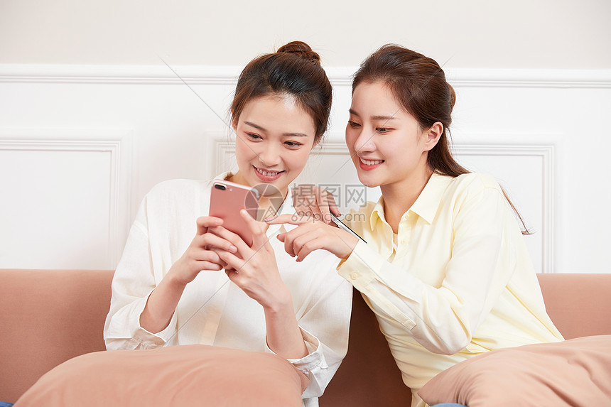 年轻闺蜜居家客厅玩手机图片