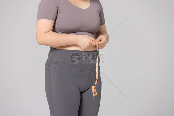 女性使用卷尺测量腰围的特写图片