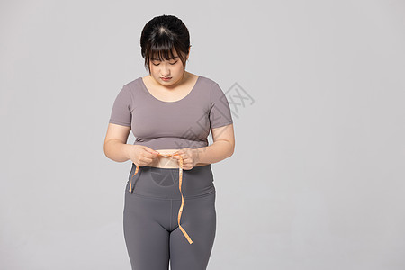 肥胖女性低头看卷尺测量腰围图片