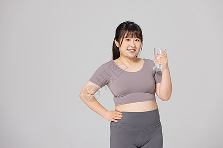 穿着健身衣的肥胖女性拿着水杯高清图片