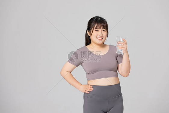 穿着健身衣的肥胖女性拿着水杯图片