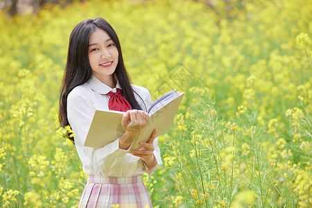 春天油菜花花海中的少女看书背景