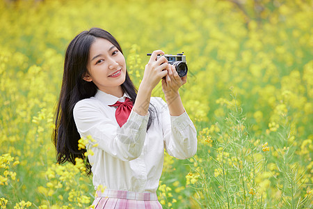 油菜花花海中的少女拍照高清图片