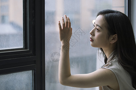 在窗前难过哭泣悲伤的女性图片素材