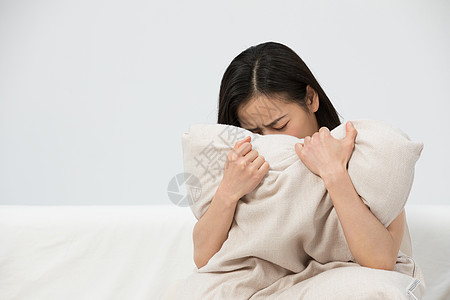 女性抱着枕头哭泣图片素材