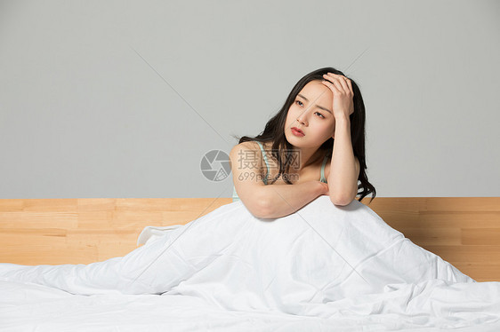 坐在床上悲伤难过的女性图片