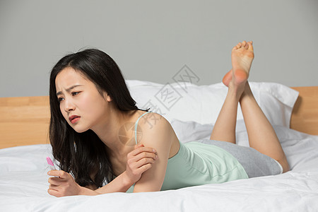 拿着验孕棒表情苦恼的女性图片