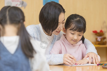 一个小女孩幼儿园老师教小女孩写字背景