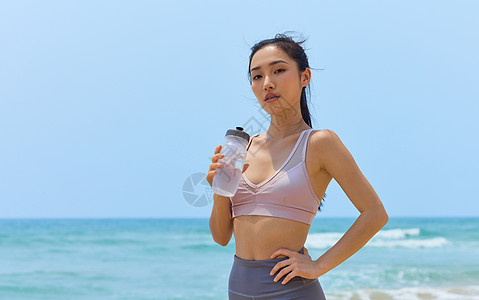 健身美女运动美女海边休息喝水背景