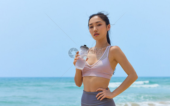 运动美女海边休息喝水图片