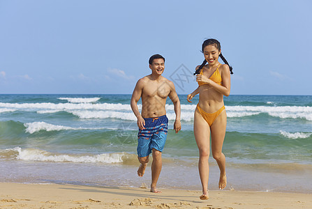 年轻情侣在海边奔跑嬉戏背景