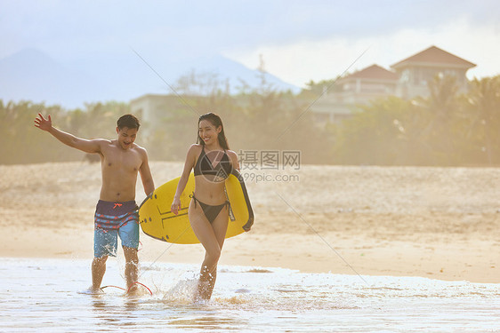 年轻男女手拿冲浪板海边行走图片