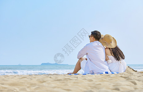 海边情侣坐在沙滩看大海背影图片