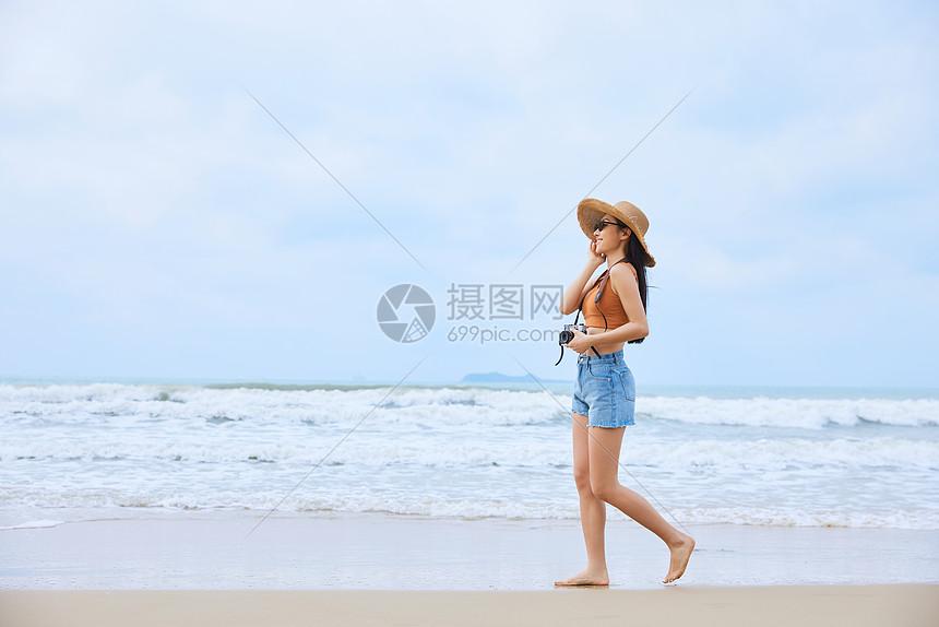 年轻美女手拿相机海边旅行图片