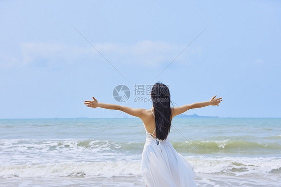 夏日海边美女张开手臂背影图片