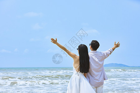 年轻情侣张开手臂拥抱大海图片