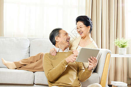 快乐的老年夫妇在客厅使用平板电脑图片