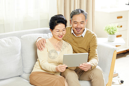看剧快乐的老年夫妇在客厅使用平板电脑背景
