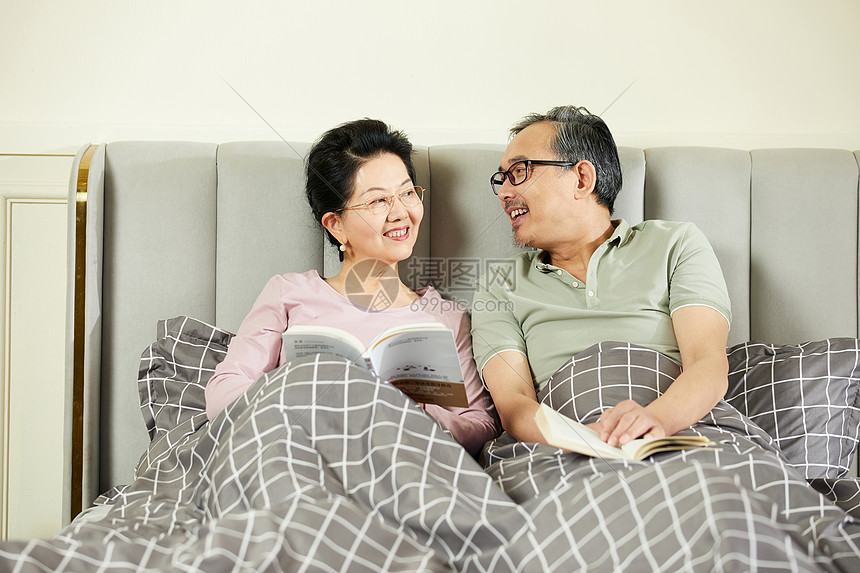 中老年夫妇坐在床上享受阅读的乐趣图片