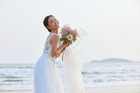 国外婚纱照海边穿婚纱的美女手拿手捧花背景