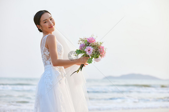 海边婚纱美女手拿手捧花图片