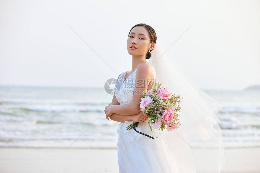 海边婚纱美女手拿手捧花图片