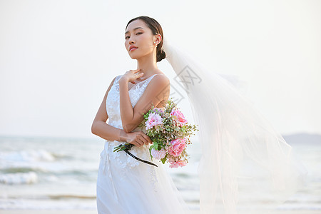 海边婚纱美女手拿手捧花图片