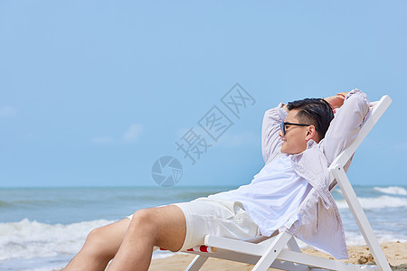 年轻男生海边度假沙滩椅上休息图片
