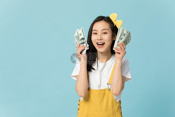 拿着钞票表情开心的年轻女性图片