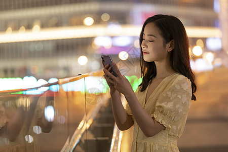 夜晚女性站在桥上使用手机图片