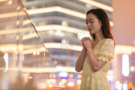 夜晚在城市祈祷的年轻女性图片