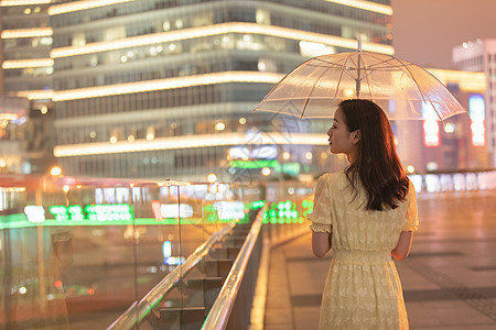 城市里撑着伞散步的女性背影背景图片