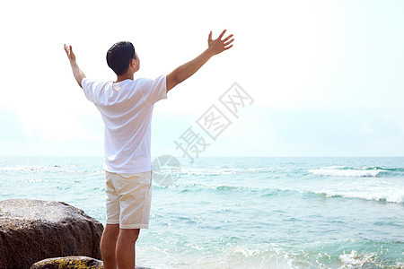 男青年张开手臂拥抱大海背影图片