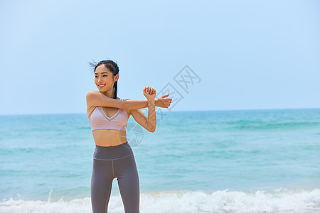 年轻美女海边运动拉伸图片