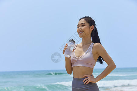 年轻美女海边运动休息喝水图片