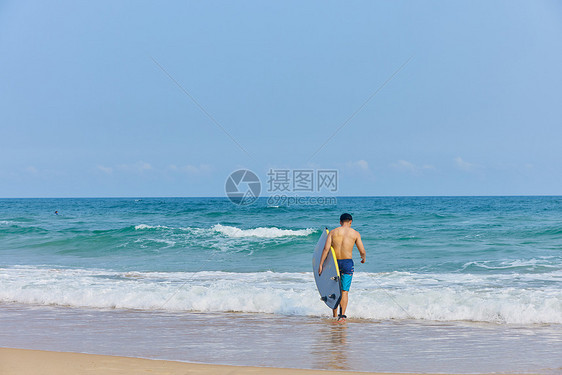 年轻男士拿着冲浪板海边行走图片